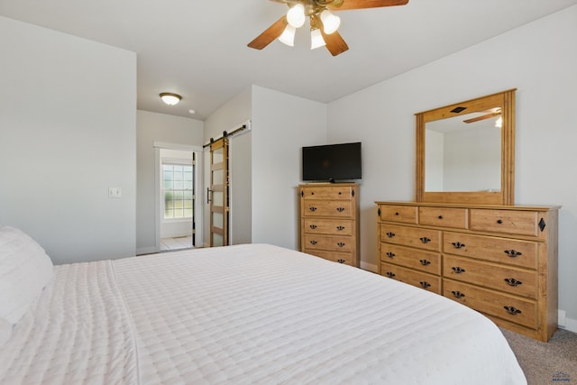 bedroom with baseboards, ceiling fan, carpet, and a barn door