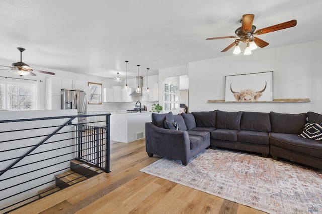 living area with a ceiling fan and light wood-style flooring