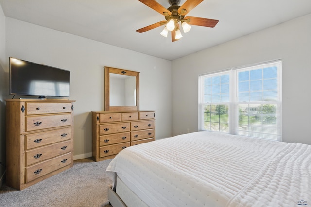 bedroom featuring light colored carpet, baseboards, and ceiling fan