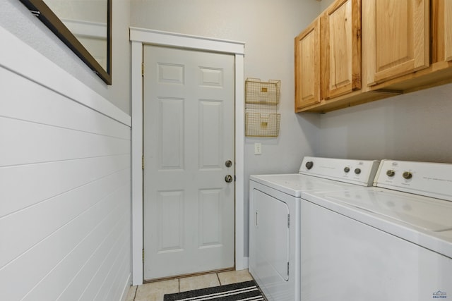 clothes washing area featuring cabinet space, light tile patterned floors, and washing machine and clothes dryer