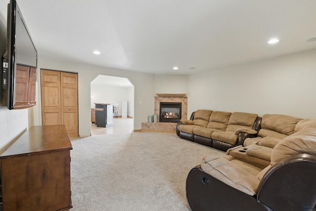 carpeted living room featuring a high end fireplace, arched walkways, and recessed lighting