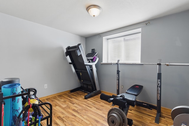 workout area with baseboards and wood finished floors