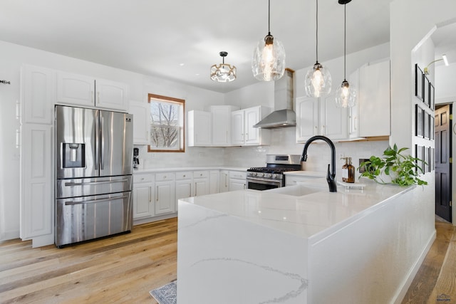 kitchen featuring decorative backsplash, appliances with stainless steel finishes, light stone counters, a peninsula, and wall chimney exhaust hood