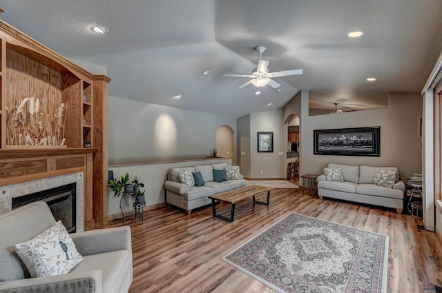 6642 Carnoustie Ct, Rapid City, SD 57702 - living room featuring light wood-type flooring, a fireplace, ceiling fan, vaulted ceiling, and arched walkways