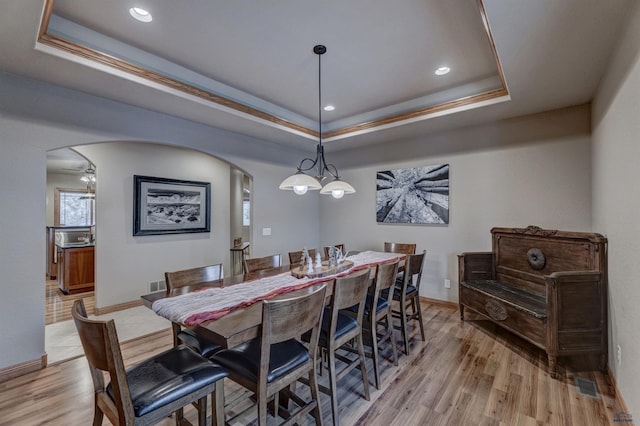 6642 Carnoustie Ct, Rapid City, SD 57702 - dining space featuring visible vents, light wood-style flooring, a raised ceiling, and arched walkways