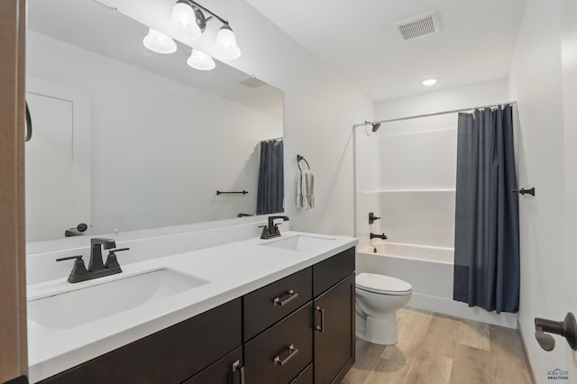 bathroom with a sink, toilet, visible vents, and wood finished floors