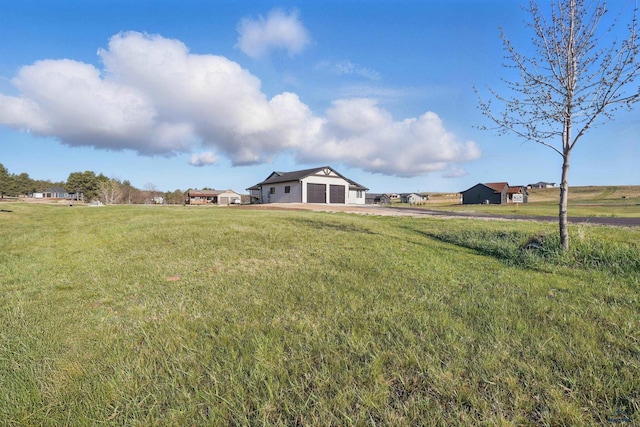 view of yard with a rural view, driveway, and a garage