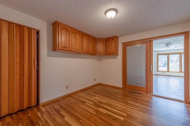 unfurnished bedroom with a textured ceiling, baseboards, light wood-type flooring, and a closet