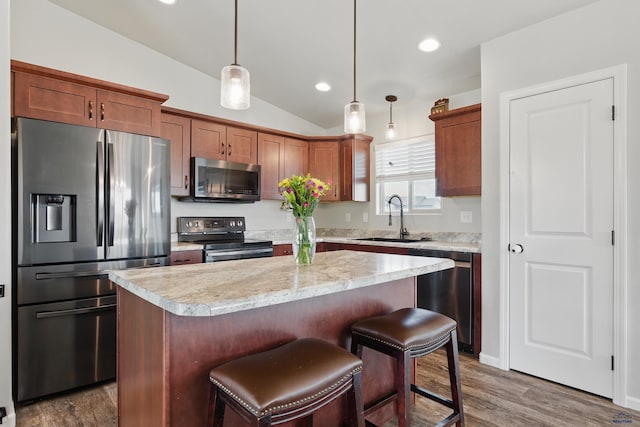 kitchen with stainless steel appliances, a sink, light countertops, a center island, and pendant lighting
