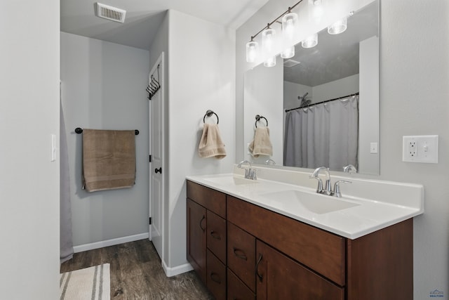 full bath featuring wood finished floors, baseboards, and double vanity