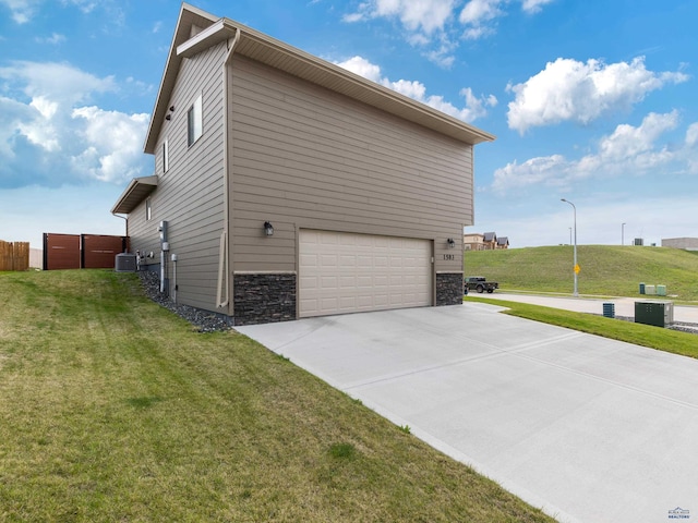 view of property exterior with an attached garage, concrete driveway, stone siding, and a lawn