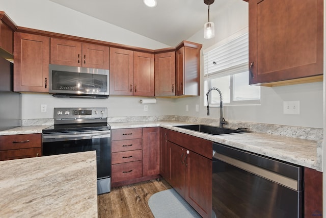kitchen with stainless steel appliances, a sink, vaulted ceiling, dark wood finished floors, and light countertops