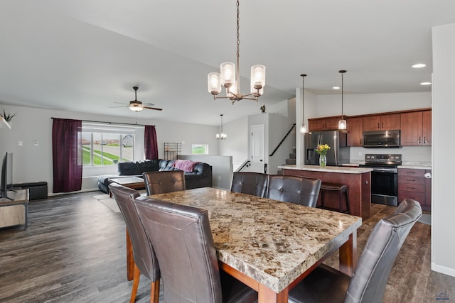 dining room featuring lofted ceiling, dark wood finished floors, a chandelier, a ceiling fan, and stairway