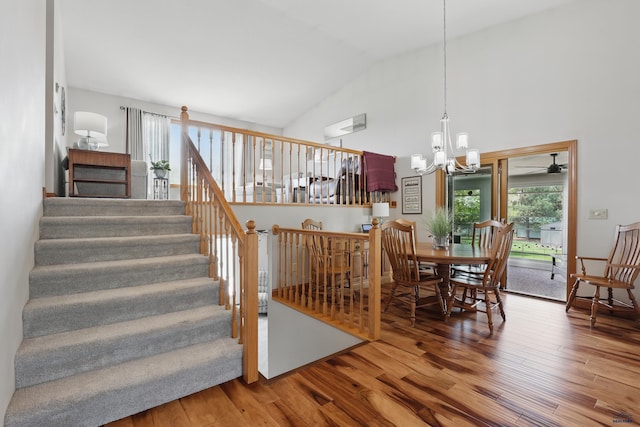 7315 Raven Ct, Rapid City, SD 57702 - dining space featuring wood finished floors, a chandelier, high vaulted ceiling, and stairs
