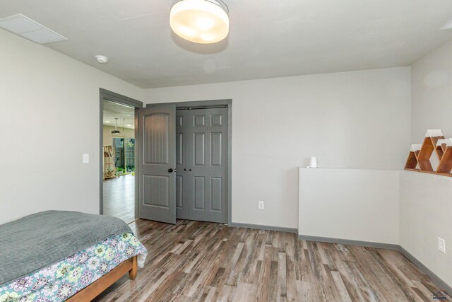 bedroom featuring wood finished floors, baseboards, and a closet