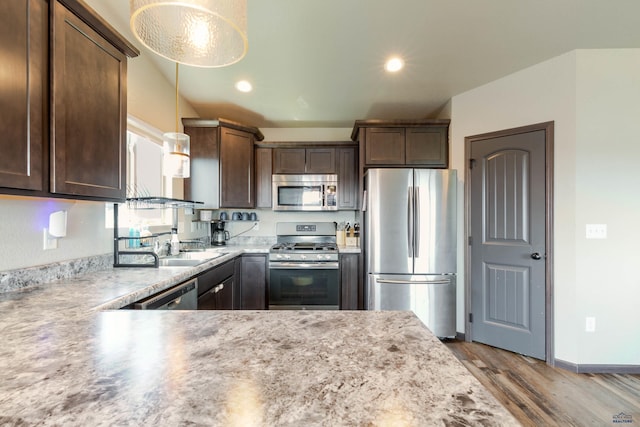 kitchen featuring appliances with stainless steel finishes, dark brown cabinetry, wood finished floors, recessed lighting, and pendant lighting