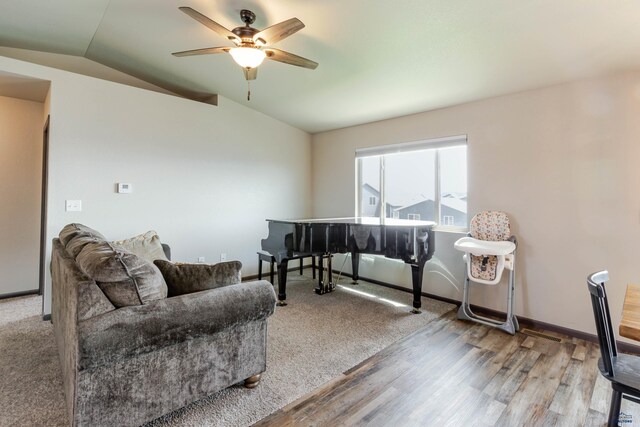 living area featuring vaulted ceiling, a ceiling fan, wood finished floors, and baseboards