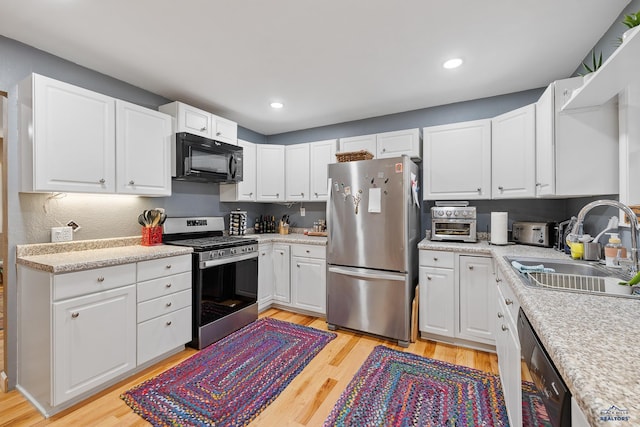 1580 Laurel Heights Dr, Rapid City, SD 57701 - kitchen featuring black appliances, a sink, light wood-type flooring, white cabinetry, and light countertops