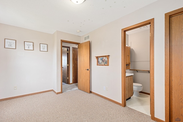 unfurnished bedroom with light colored carpet, baseboards, and ensuite bath