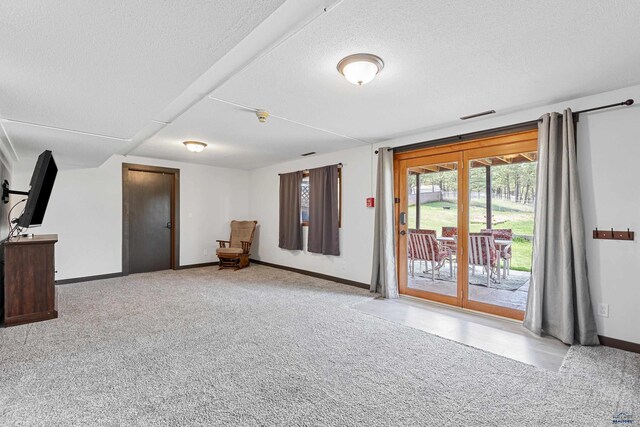 unfurnished living room with baseboards, carpet floors, and a textured ceiling