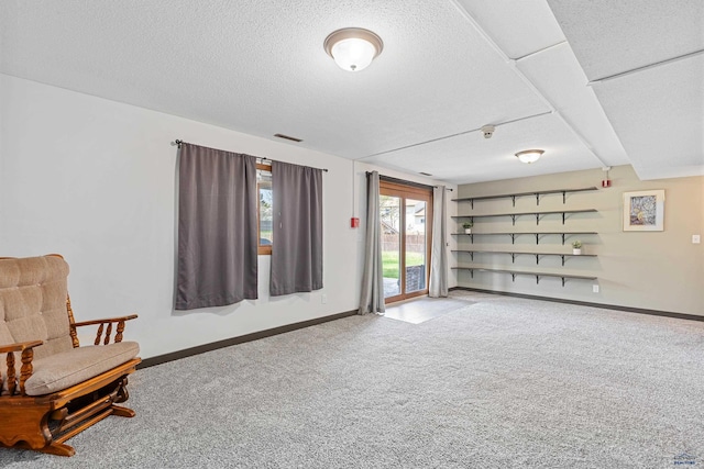 sitting room with carpet flooring, baseboards, and a textured ceiling