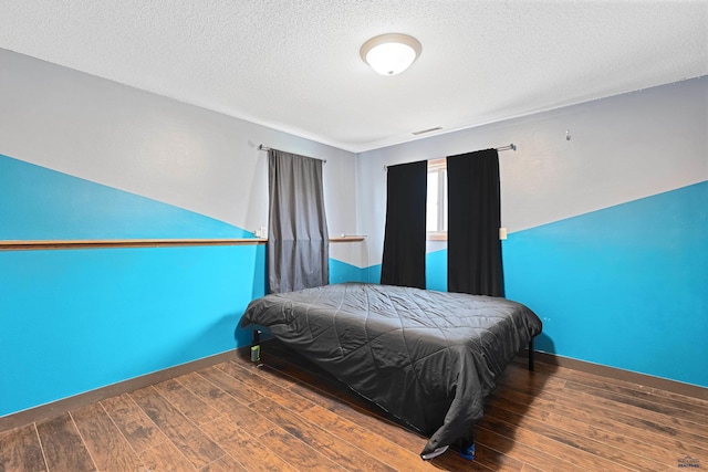 bedroom featuring wood finished floors, a textured ceiling, and baseboards