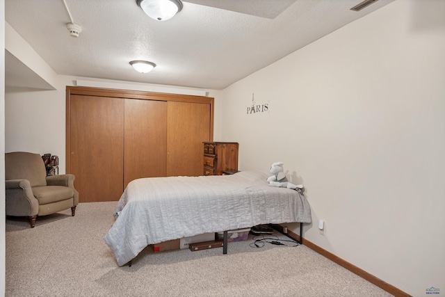 bedroom with carpet, a closet, baseboards, and a textured ceiling