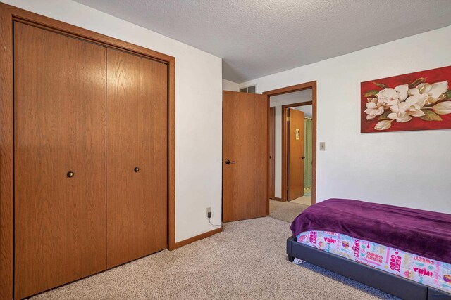 bedroom featuring light carpet, a closet, and a textured ceiling