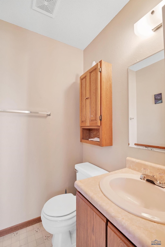 half bath featuring toilet, vanity, and baseboards