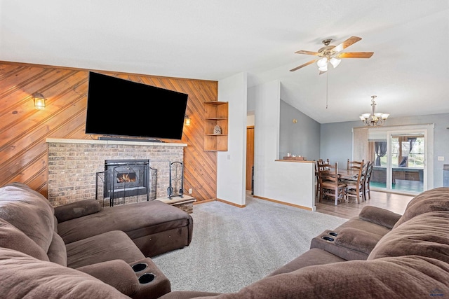 carpeted living area with wooden walls, a ceiling fan, baseboards, lofted ceiling, and a chandelier
