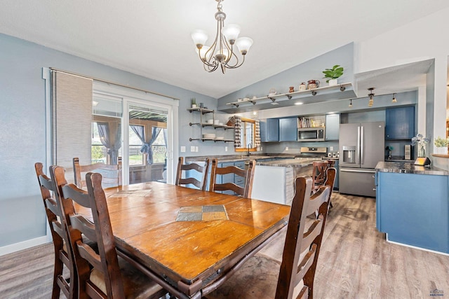 dining area with a chandelier, light wood finished floors, vaulted ceiling, and baseboards