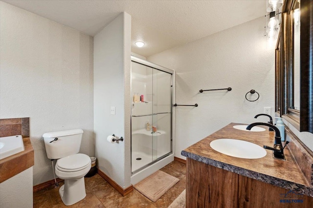 bathroom featuring a shower stall, toilet, baseboards, double vanity, and a textured ceiling