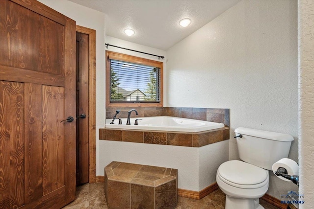 full bathroom featuring toilet, a garden tub, and a textured wall
