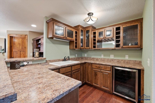 bar area featuring beverage cooler, a sink, dark wood finished floors, and a textured ceiling