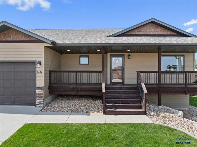 view of front of house with covered porch, an attached garage, a shingled roof, and stairs