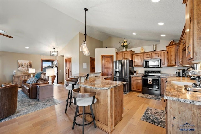kitchen featuring appliances with stainless steel finishes, open floor plan, a kitchen bar, light wood-style flooring, and high vaulted ceiling