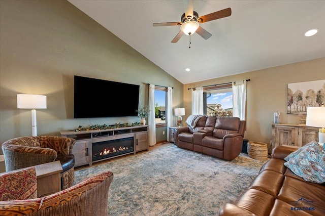 living room with a ceiling fan, high vaulted ceiling, a lit fireplace, and recessed lighting