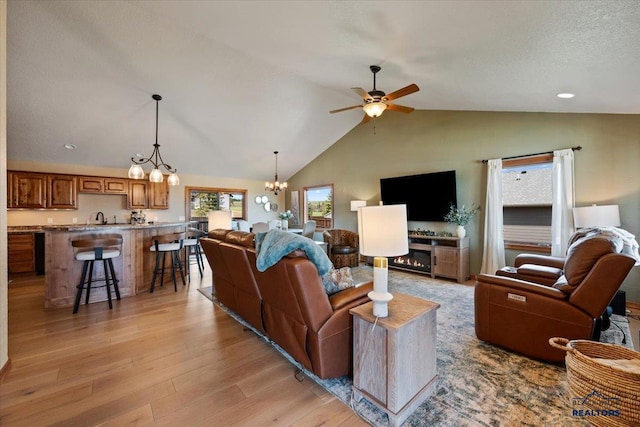 living area featuring ceiling fan, light wood finished floors, vaulted ceiling, a chandelier, and recessed lighting