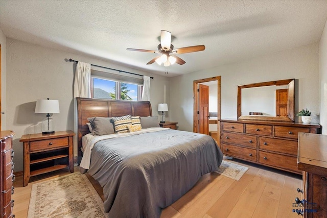 bedroom featuring light wood-style floors, a textured ceiling, and ceiling fan