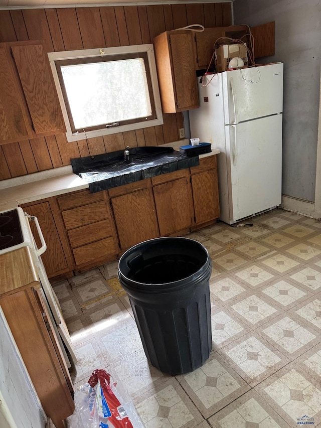 kitchen with freestanding refrigerator, light flooring, and brown cabinetry