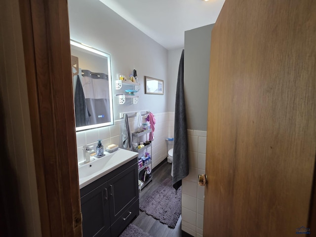 142 W Summit, Lead, SD 57754 - bathroom with wood finished floors, vanity, tile walls, toilet, and a wainscoted wall