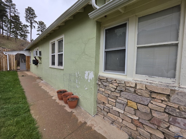 142 W Summit, Lead, SD 57754 - view of property exterior featuring stucco siding, an AC wall unit, stone siding, and fence