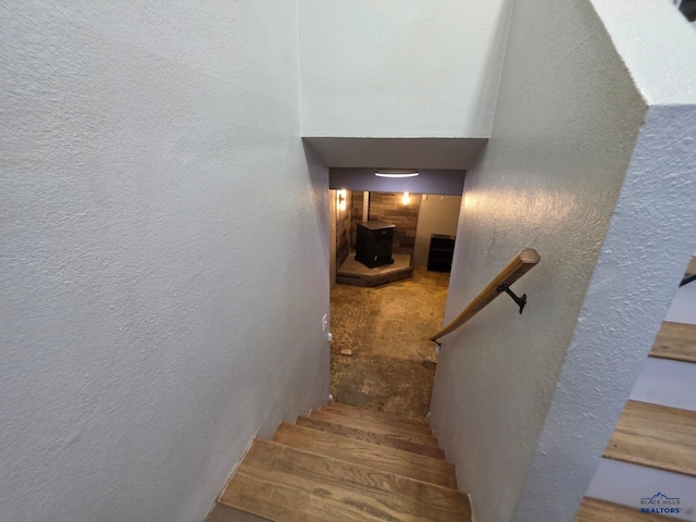 staircase featuring a textured wall and wood finished floors