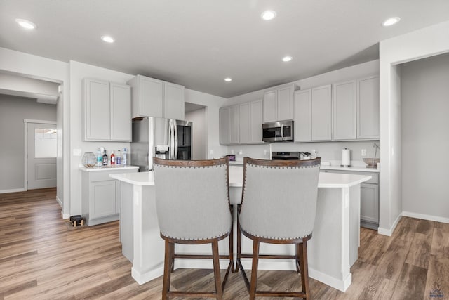 506 Solomon Ct, Rapid City, SD 57703 - kitchen featuring stainless steel appliances, a kitchen island, a kitchen bar, light countertops, and light wood finished floors