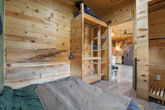 24427 Thovson Rd, Keystone, SD 57751 - bedroom with wood walls, stainless steel refrigerator with ice dispenser, wooden ceiling, and wood finished floors