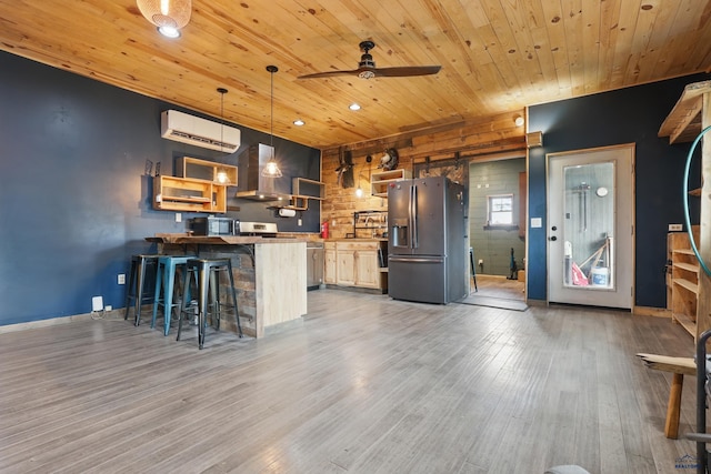 24427 Thovson Rd, Keystone, SD 57751 - kitchen featuring appliances with stainless steel finishes, an AC wall unit, wood ceiling, a barn door, and wall chimney exhaust hood