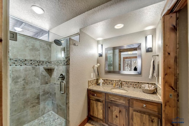 21172 Last Chance Trl, Lead, SD 57754 - full bathroom with a textured wall, a textured ceiling, a stall shower, backsplash, and vanity