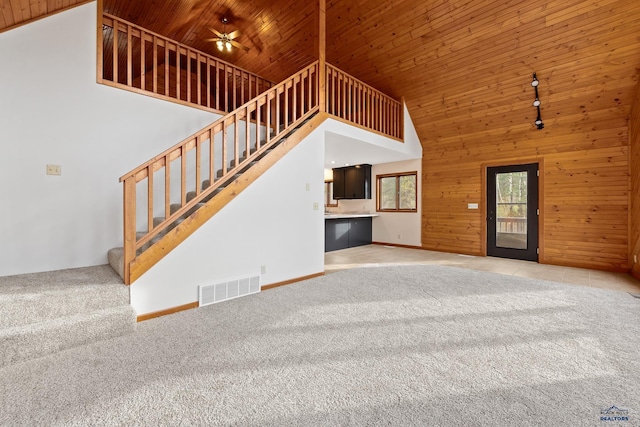 12087 Kaubisch Ranch Rd, Hill City, SD 57745 - unfurnished living room with light carpet, wooden ceiling, high vaulted ceiling, wood walls, and stairs