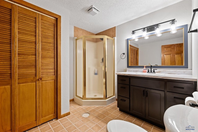 12087 Kaubisch Ranch Rd, Hill City, SD 57745 - full bath with a textured ceiling, a stall shower, tile patterned flooring, a closet, and vanity