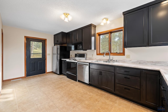 12087 Kaubisch Ranch Rd, Hill City, SD 57745 - kitchen with stainless steel appliances, a sink, light countertops, a textured ceiling, and baseboards